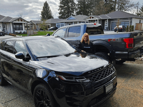 a woman stands in front of a black range rover and a ford f150 truck