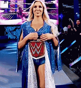 a woman in a blue and white dress is standing on a stage holding a belt with a w on it .