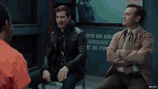a group of men are sitting in a room with a sign that says loud or abusive language must be permitted .