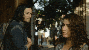 a man and a woman are looking at each other on a street