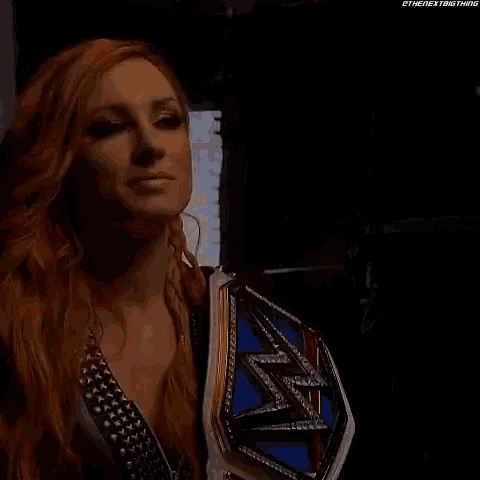 a woman with long red hair is holding a championship belt