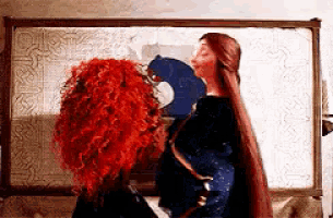 a woman with red hair is kissing another woman with long hair .