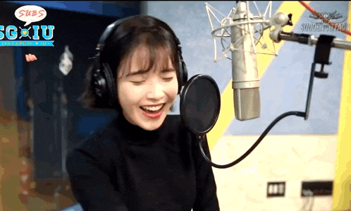 a woman wearing headphones is smiling in front of a microphone with a speech bubble that says subs on it