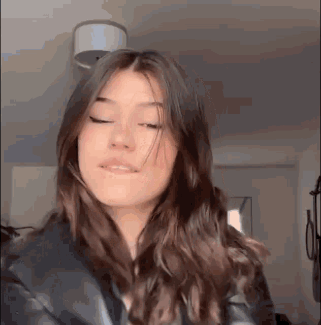 a young woman with long brown hair is wearing a black leather jacket .