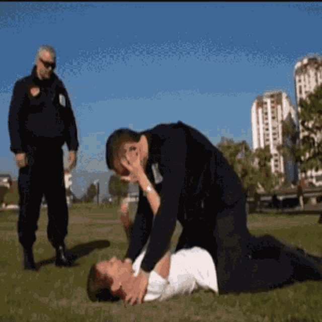 a man is kneeling over a woman who is laying on the grass
