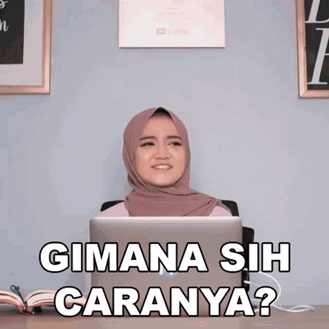 a woman in a hijab sits at a desk with a laptop and says gimana sih caranya ?