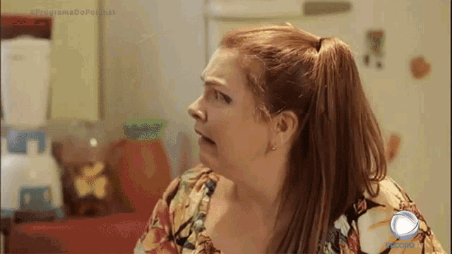 a woman with a ponytail looks at something in front of a refrigerator that says programa do porchat