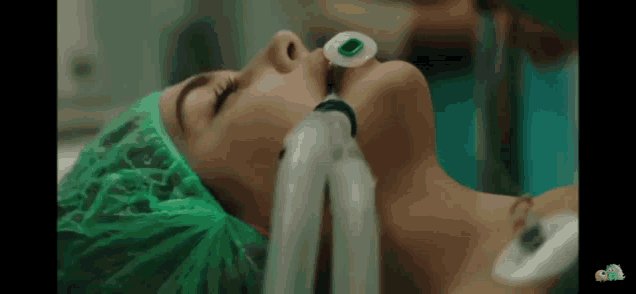 a woman is laying in an operating room with an oxygen mask around her neck .