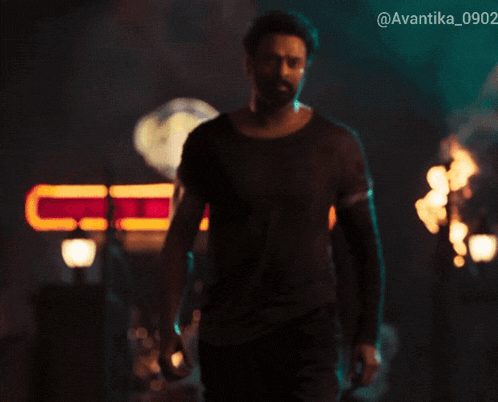 a man in a black shirt stands in front of a sign that says avantika 0902