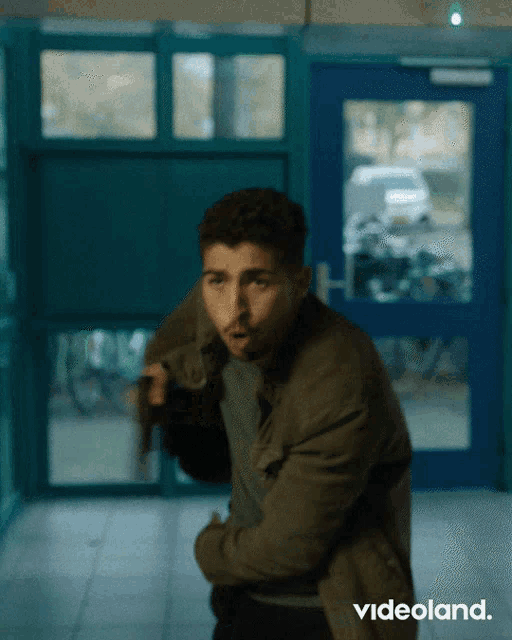 a man in a green jacket is walking through a hallway with videoland written on the bottom