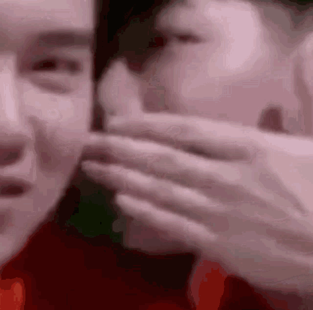 a man is covering another man 's mouth with his hand .