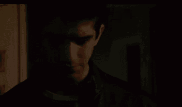 a man with red eyes is standing in a dark room .