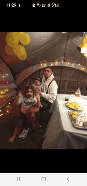 a man and two children are sitting at a table in a tent