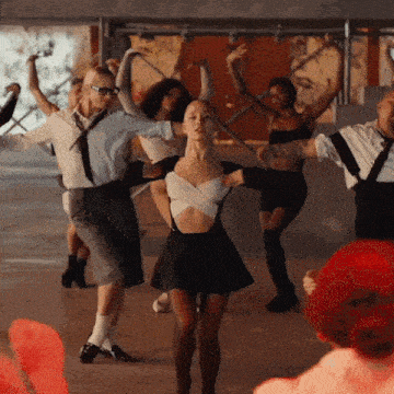 a group of people are dancing in a room with a red hat in the background