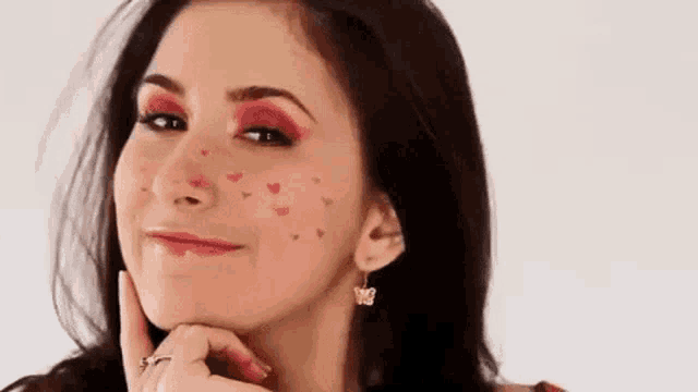 a woman with red makeup and hearts on her face is smiling .