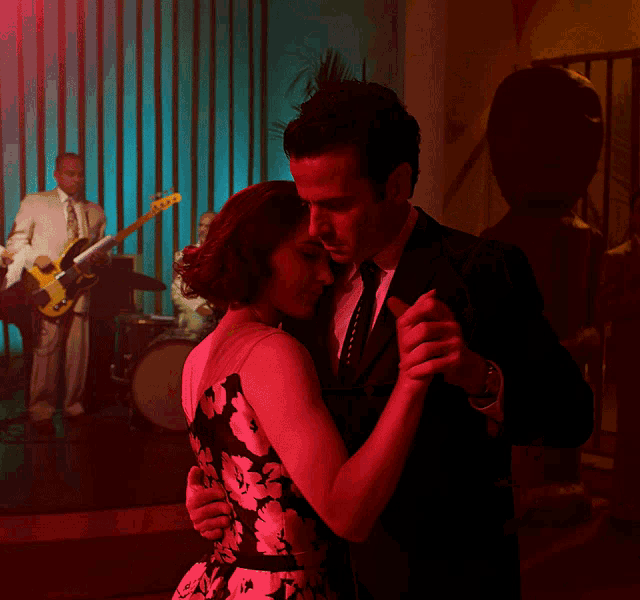 a man in a suit and tie is dancing with a woman in a dress