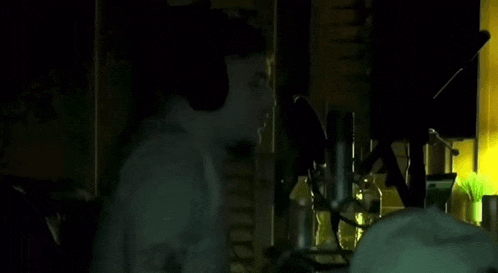 a man is standing in front of a microphone in a dark room .