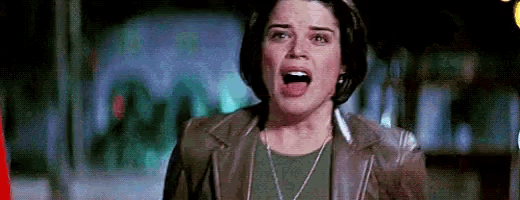 a woman in a leather jacket is screaming with her mouth open in a dark room .