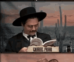 gabriel prior is reading a book while wearing a hat and glasses