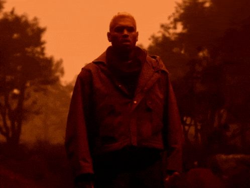 a man in a red jacket is standing in the dark