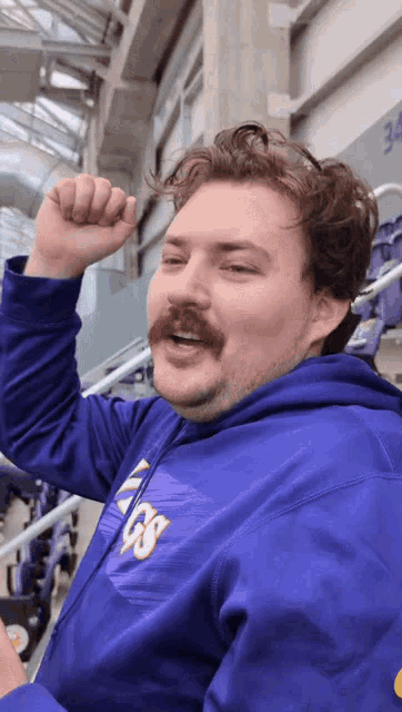 a man with a mustache wearing a purple hoodie that says vikings