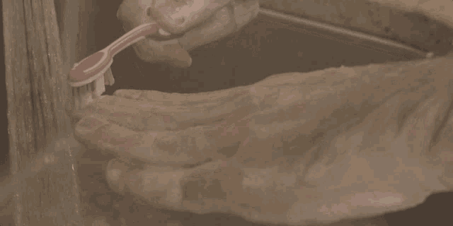 a person washing their hands with a pink toothbrush