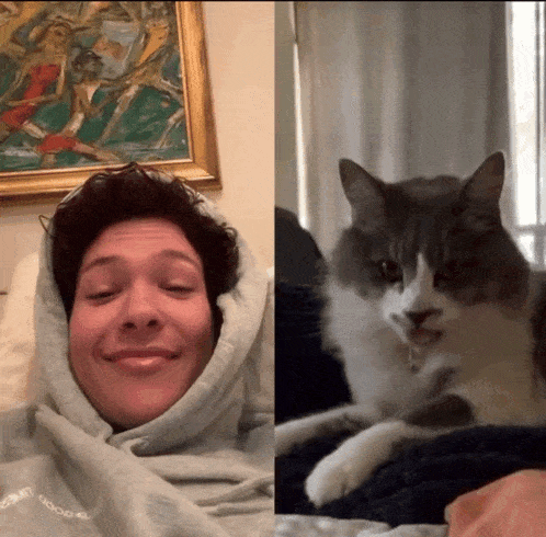 a man wearing a hoodie with the word good on it is next to a cat