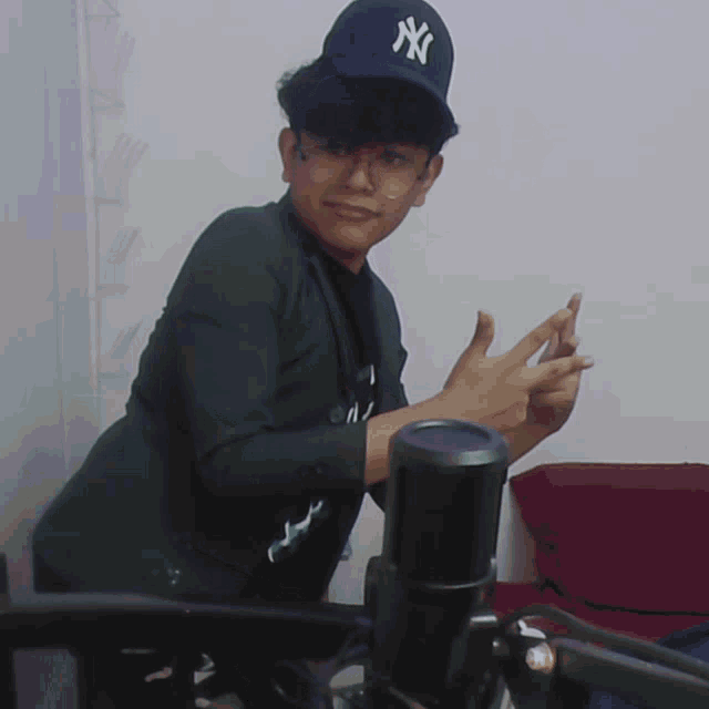 a young man wearing a ny hat is giving a thumbs up