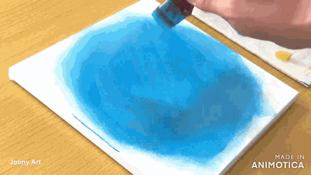 a person is painting a blue circle on a canvas that is made in animatica