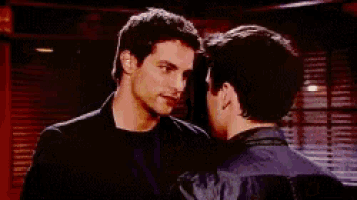 two men are touching their foreheads in a dark room