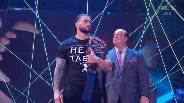 a man in a he of tae shirt is holding a championship belt
