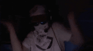 a person wearing a mask and sunglasses is standing in the dark .