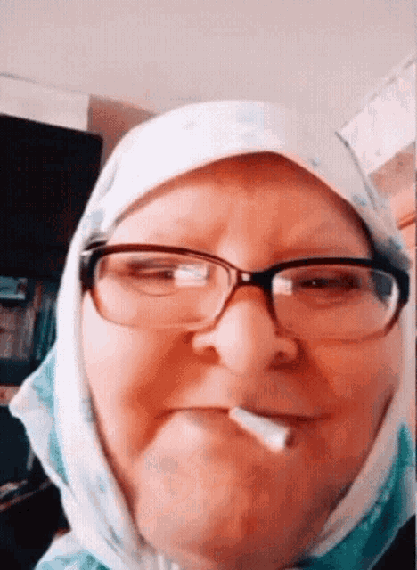 an elderly woman wearing glasses and a scarf smoking a cigarette