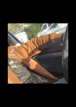 a tik tok video of a person sitting in a car with a blanket on the steering wheel