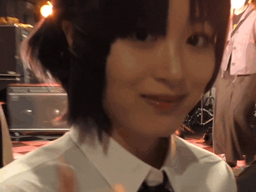 a close up of a woman 's face with a white shirt and black tie