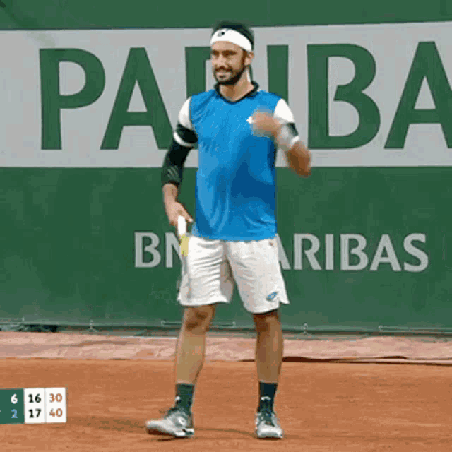 a tennis player stands in front of a bn aribas sign