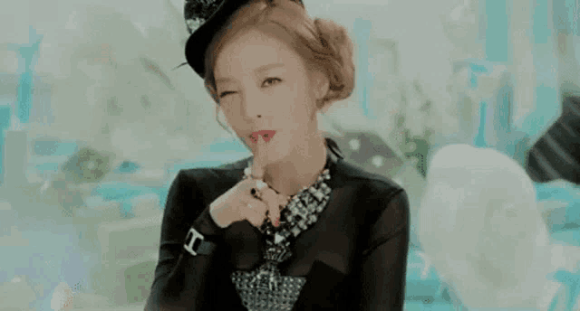 a woman wearing a hat and a necklace is making a silly face with her finger to her lips .