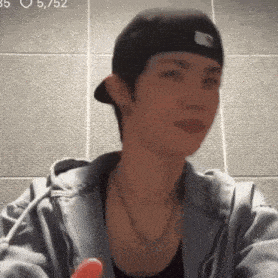 a young man wearing a hat and a hoodie is holding a red object in his hand .