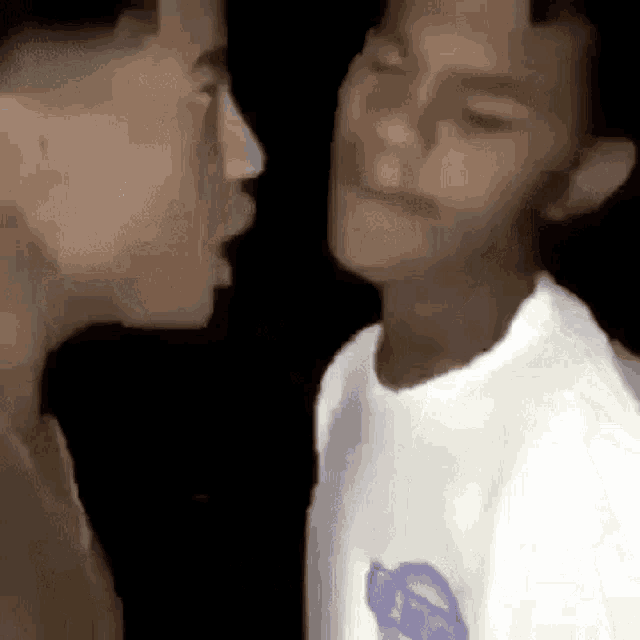 two men are kissing each other on the cheek in a video .