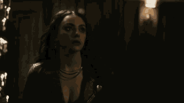a woman in a dark room with a few lights behind her