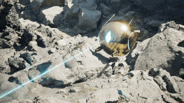 a gold sphere is sitting on a rocky surface
