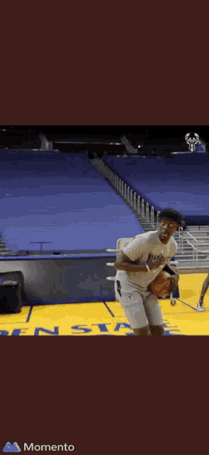a man is holding a basketball on a basketball court that says momento on it