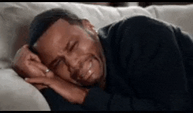a man is crying while laying on a couch with his eyes closed .