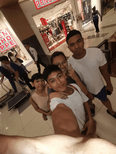a group of people are posing for a picture in front of a store that has the word pen on it
