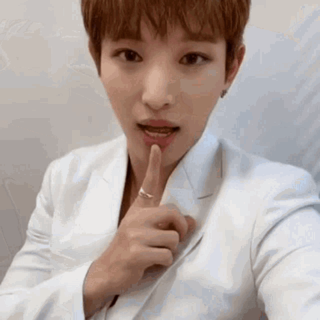 a young man is taking a selfie with his finger in his mouth .