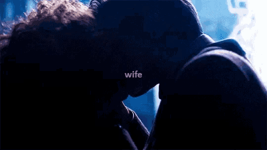 a man and woman are kissing in a dark room with the words `` wife '' written on the bottom .