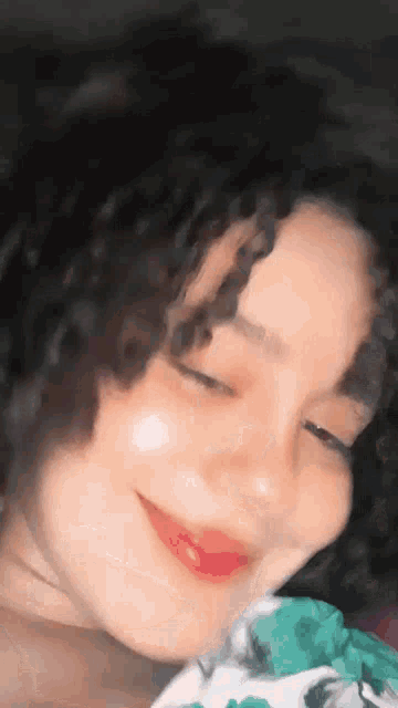 a close up of a woman with curly hair smiling with her eyes closed