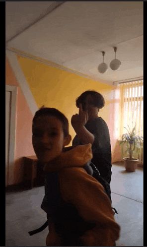 a boy in a yellow hoodie stands next to another boy