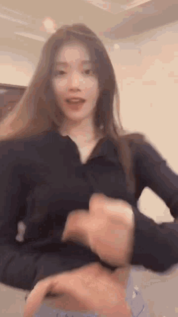a woman in a black shirt is being held by a man in a room and looking at the camera .