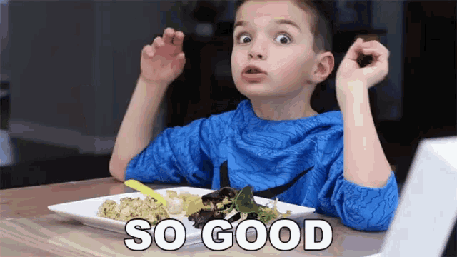 a young boy is sitting at a table with a plate of food and the words so good written on the table